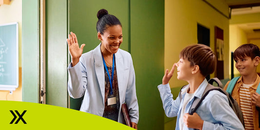 Teacher winding up to high five student as he enters classroom.