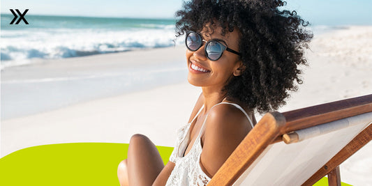 Woman relaxing in chair on beach wearing sunglasses.