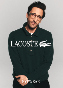 Adrien Brody wearing brown-frame Lacoste eyeglasses and a dark polo shirt in a Lacoste Eyewear campaign. 