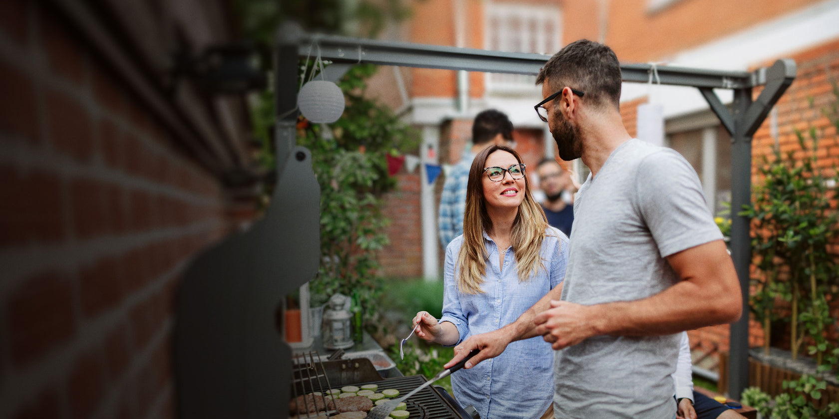 Man and woman standing on a patio, looking at a laptop screen together.