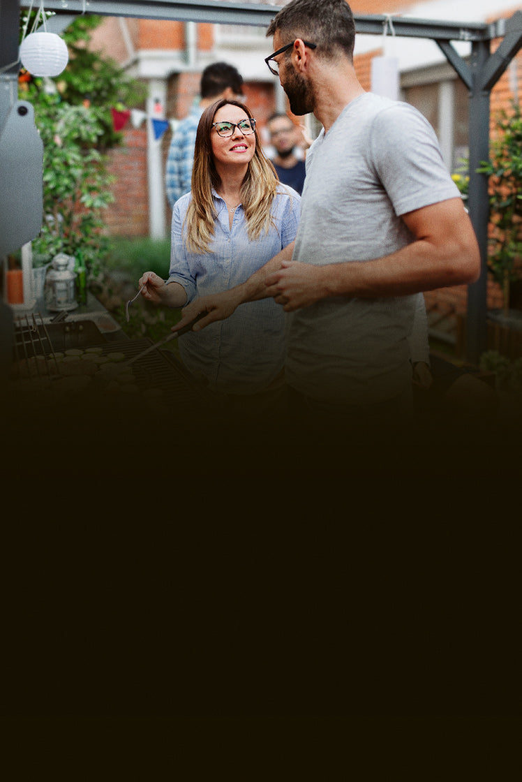 Man and woman standing on a patio, looking at a laptop screen together.